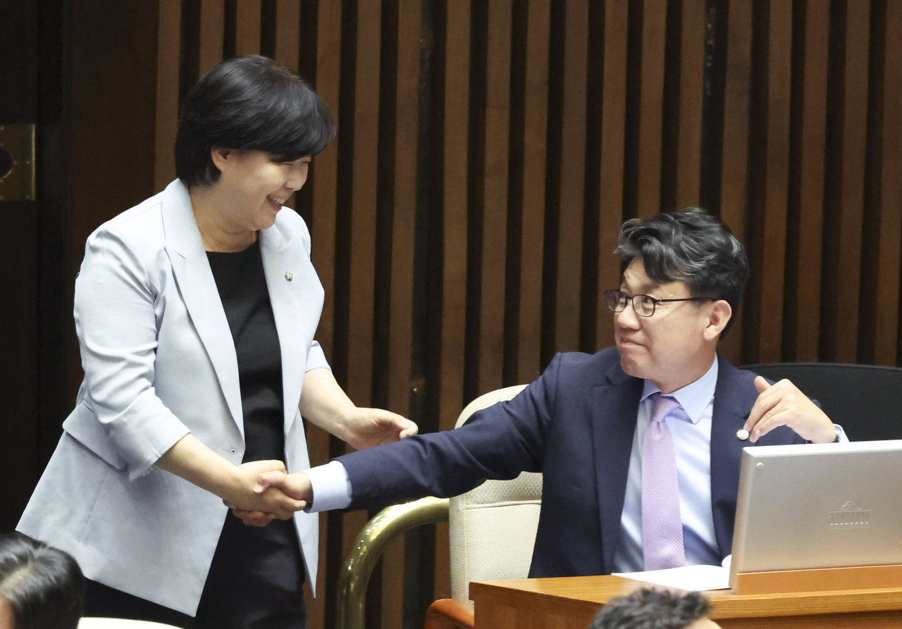 Democratic Party Reps. Seo Young-kyo (left) and Jin Sung-joon shake hands during a plenary session of the National Assembly Thursday. (Newsis)