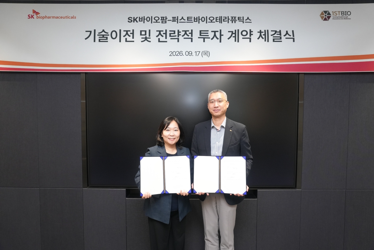 Kim Jae-eun (left), chief executive of First Bio Therapeutics, and Yoo Chang-ho, head of strategy at SK Biopharm, pose for a photo at a contract signing ceremony held at SK Biopharm's Pangyo office on Thursday. [SK Biopharm]