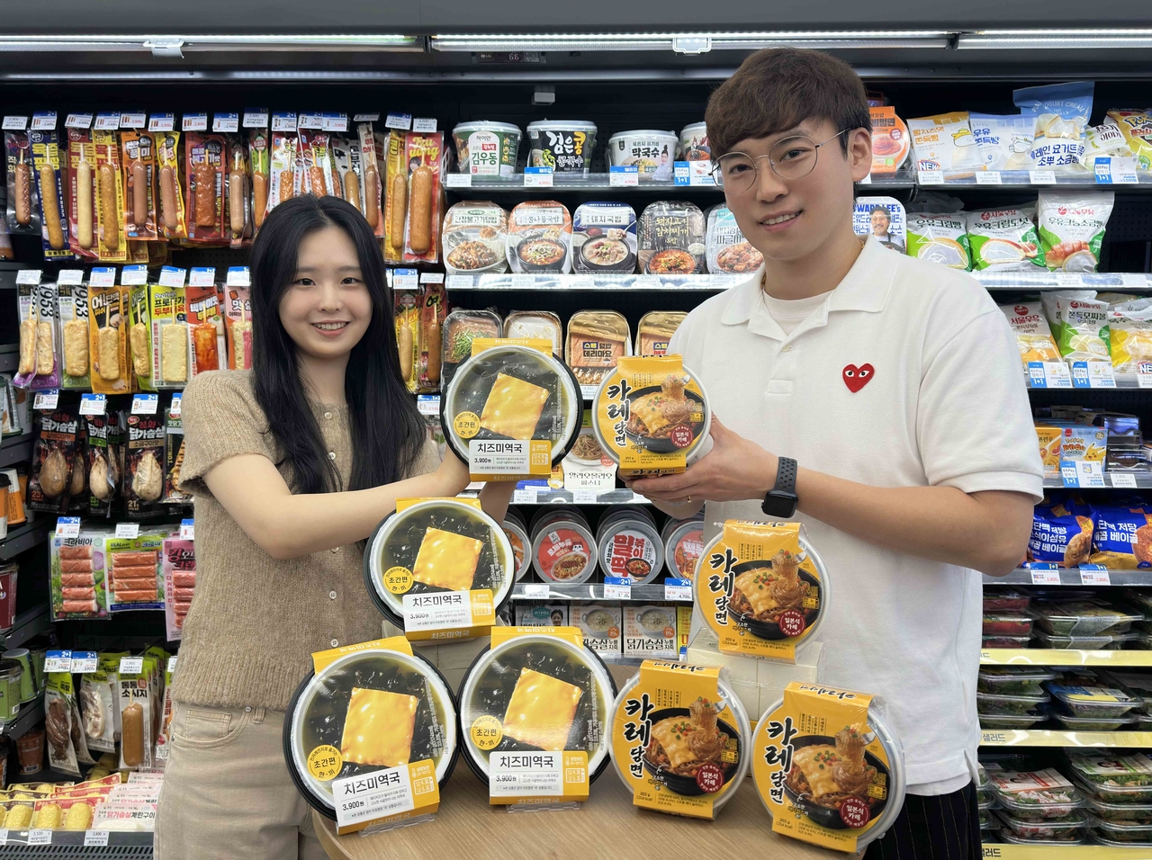 A GS25 product developer poses with the new cheese seaweed soup and curry glass noodles, both developed from viral social media recipes. [GS25]