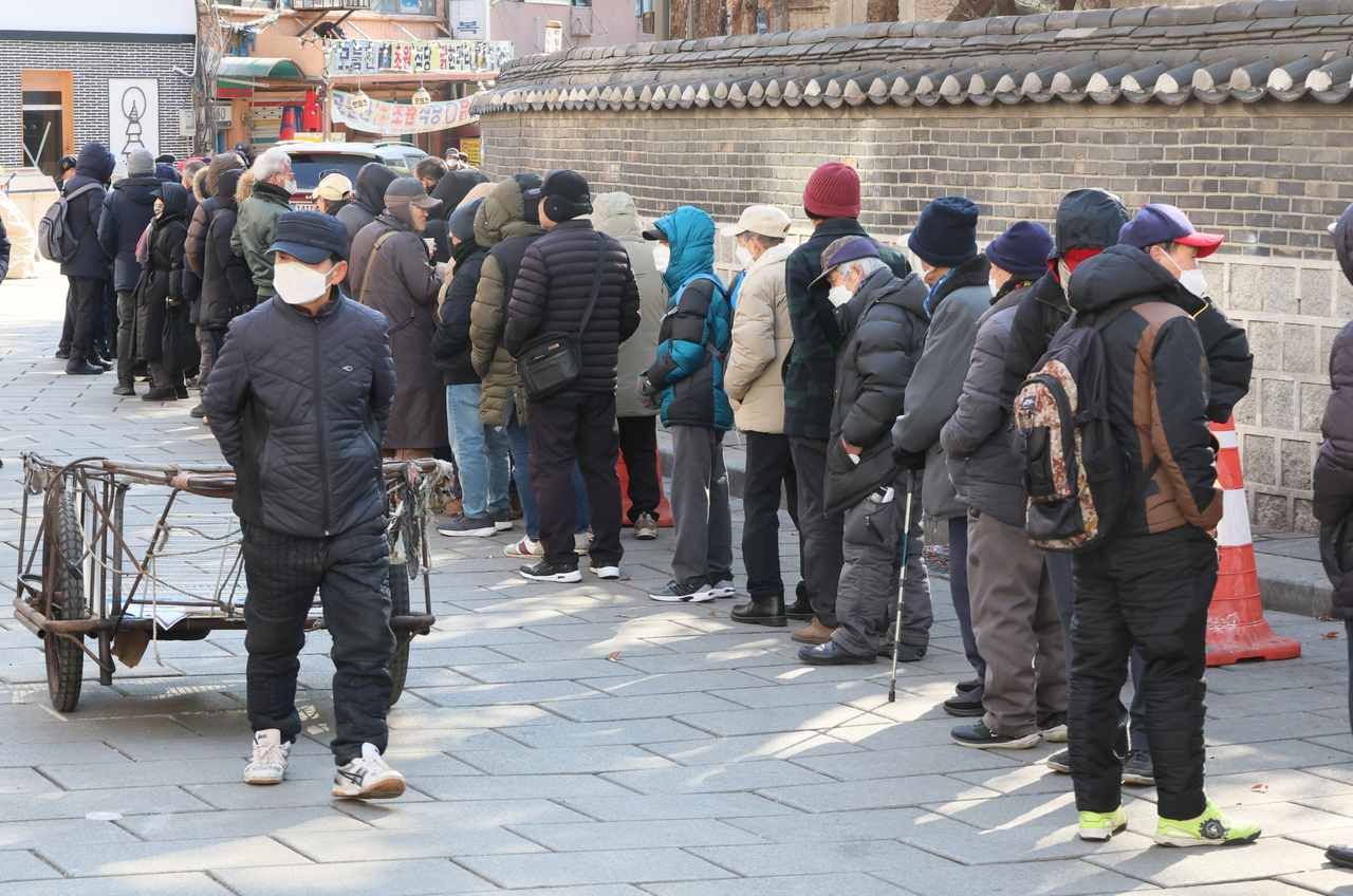 서울 종로구 탑골공원 원각사 노인무료급식소 앞에 어르신들이 점심식사를 위해 줄지어 서 있다. [연합]
