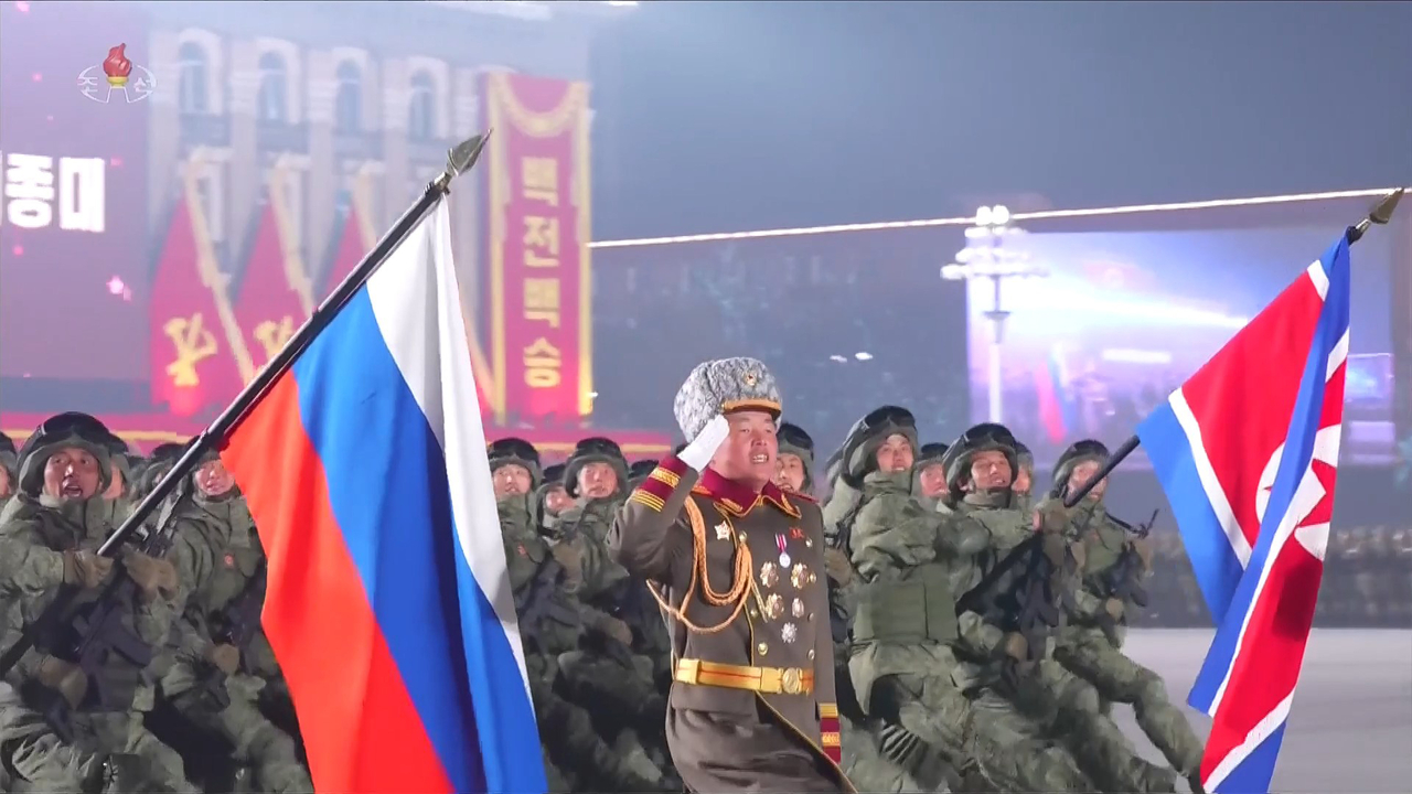 Soldiers from overseas operations units and overseas engineer regiments who were deployed to the war in Ukraine march carrying Russian and North Korean flags at a military parade marking the ninth party congress, broadcast on Korean Central Television in February. [Yonhap]