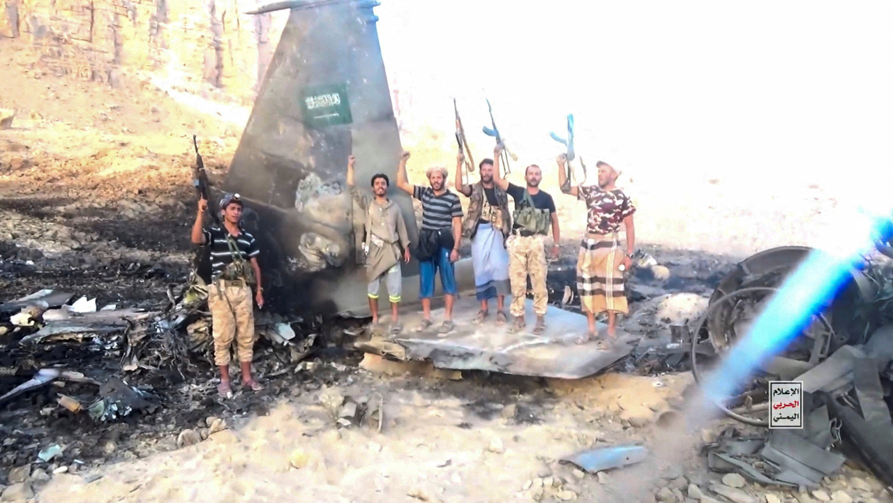 Houthi fighters stand in front of an allegedly downed Saudi jet fighter, at an undisclosed location in Yemen, Wednesday.   (Reuters-Yonhap)