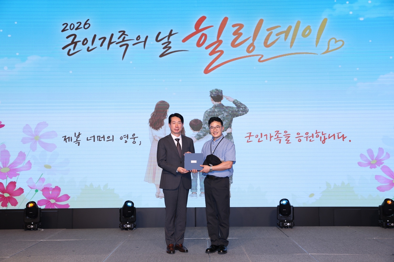 Hanwha Aerospace Executive Vice President Moon Ji-hoon poses for a photo with a representative of exemplary service members at the "Military Family Day Healing Day" event hosted by Hanwha's three defense affiliates and the Ministry of National Defense at The Plaza hotel in Seoul on Thursday. [Hanwha]