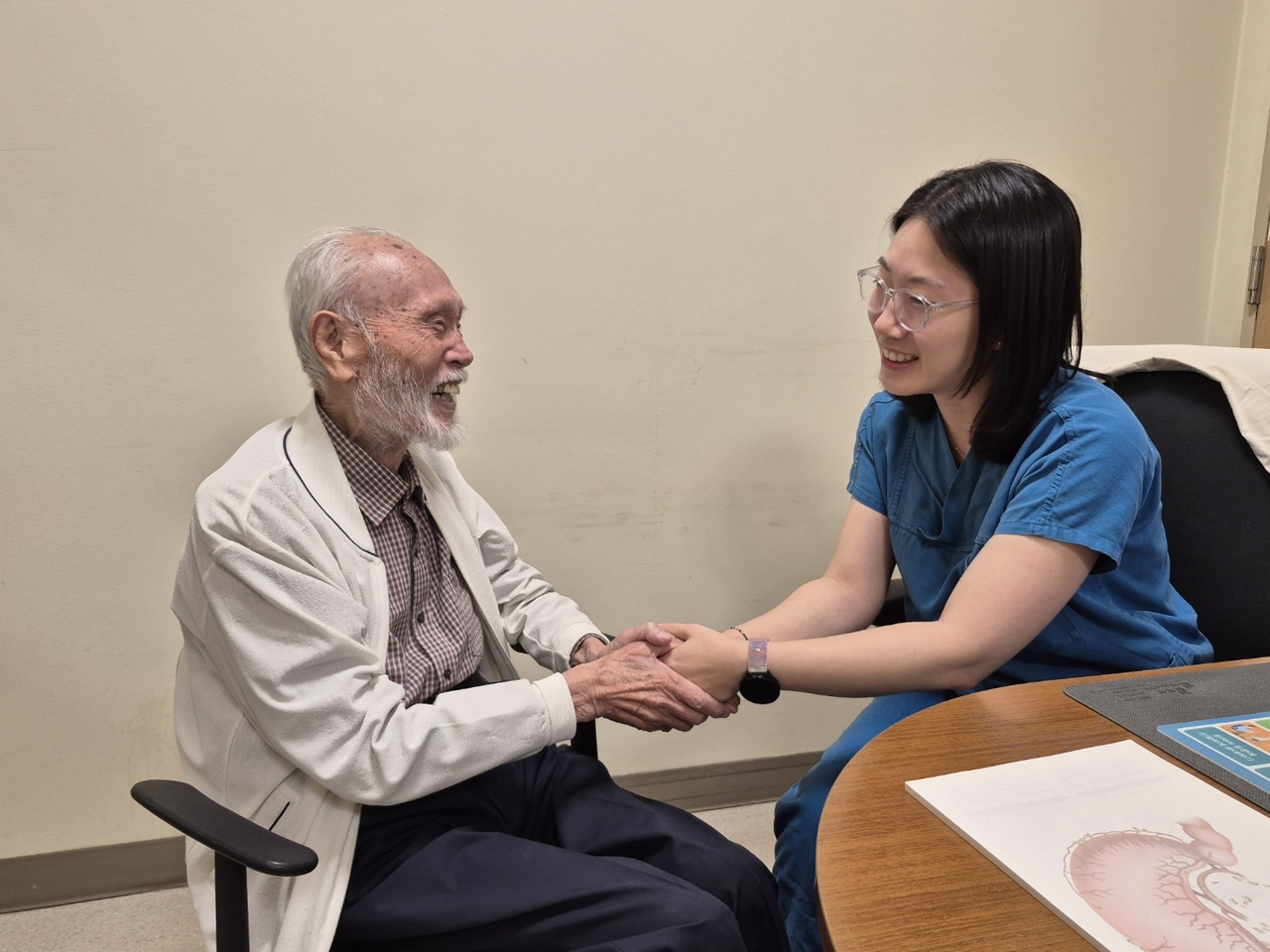 Kim So-jung, a gastrointestinal surgery professor at the Catholic University of Korea Seoul St. Mary's Hospital Gastric Cancer Center, holds the hand of the 97-year-old stomach cancer patient. [Seoul St. Mary's Hospital]