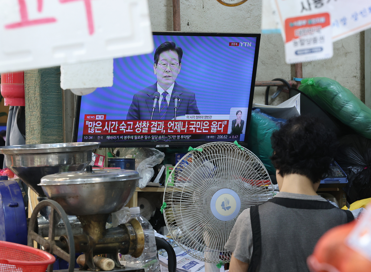 18일 서울 한 전통시장에서 상인이 생중계되는 이재명 대통령의 기자회견을 텔레비전을 통해 지켜보고 있다. [연합]