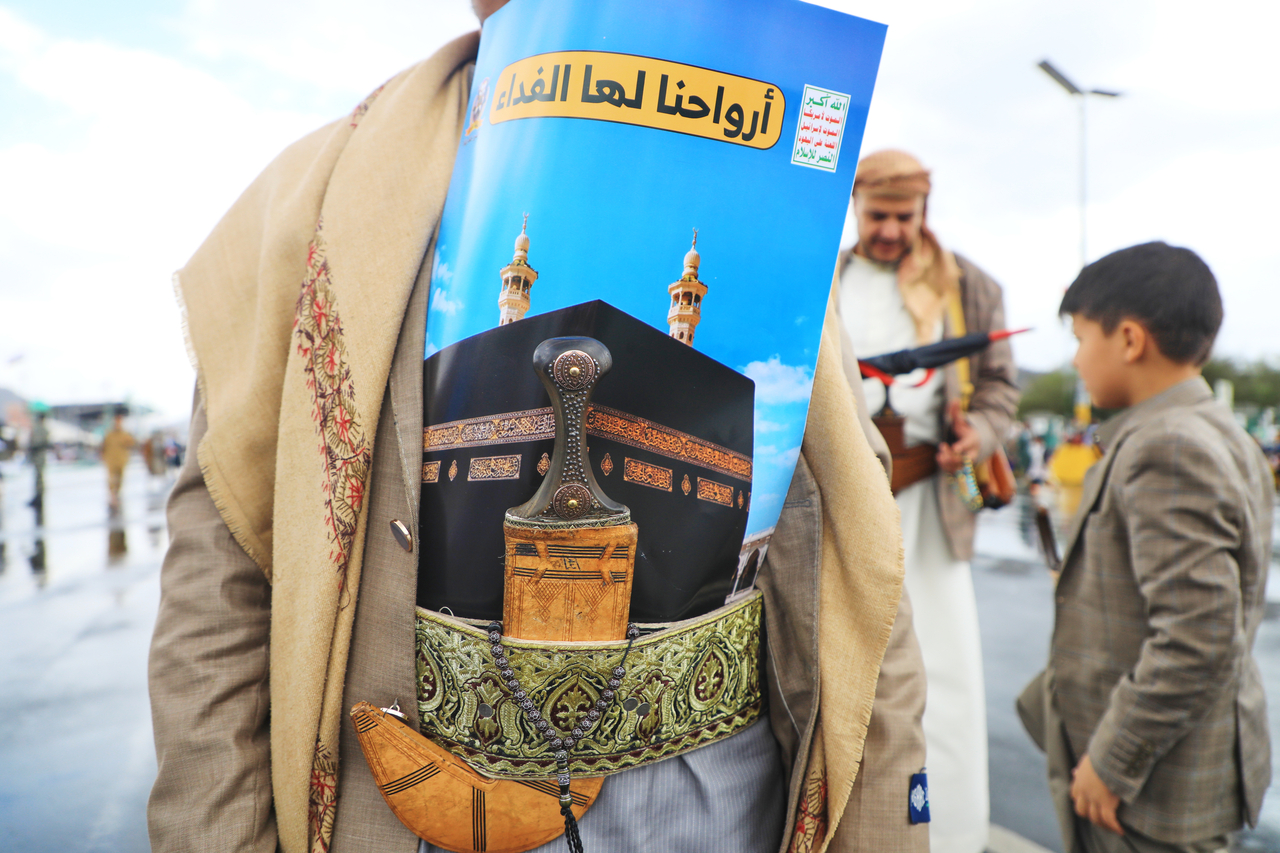 A supporter of Yemen’s Houthi rebels wears a poster showing the Kaaba at the Grand Mosque, tucked into a decorative sash above a dagger, during a rally to protest Saudi Arabia's accusation that the Houthis targeted Islam's holiest site, in Sanaa, Yemen, Friday. Arabic reads, "Our souls are sacrificed for it." (AP)