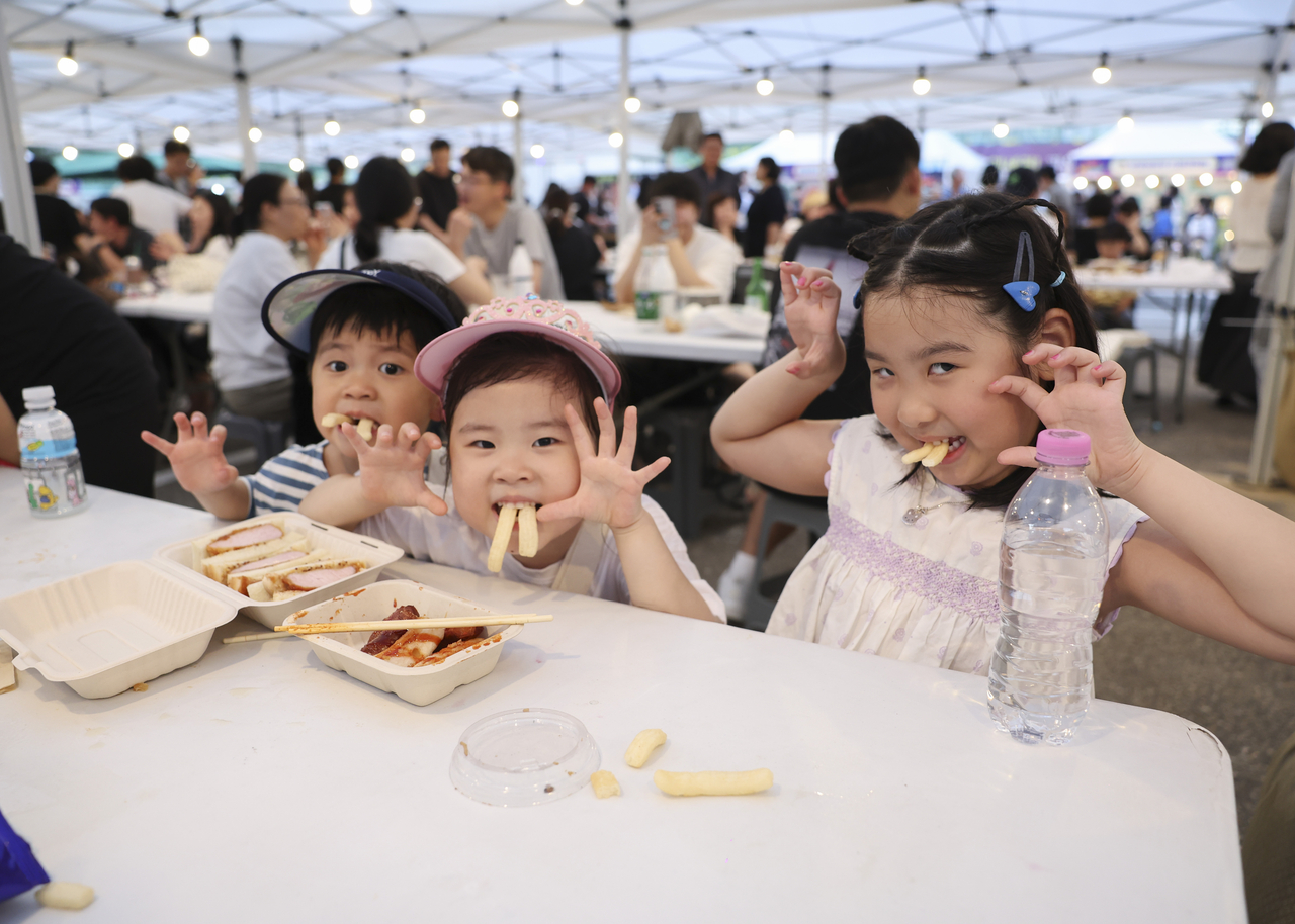 Children enjoy food and take photos at the Seokgye Station Moonlight Night Market.