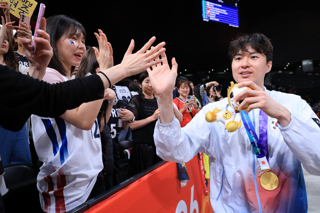 Lee Hyun-jung of South Korea (right) high-fives fans after winning gold in men's basketball at the Asian Games at Aichi International Arena in Nagoya, Japan, on Sunday. (Yonhap)