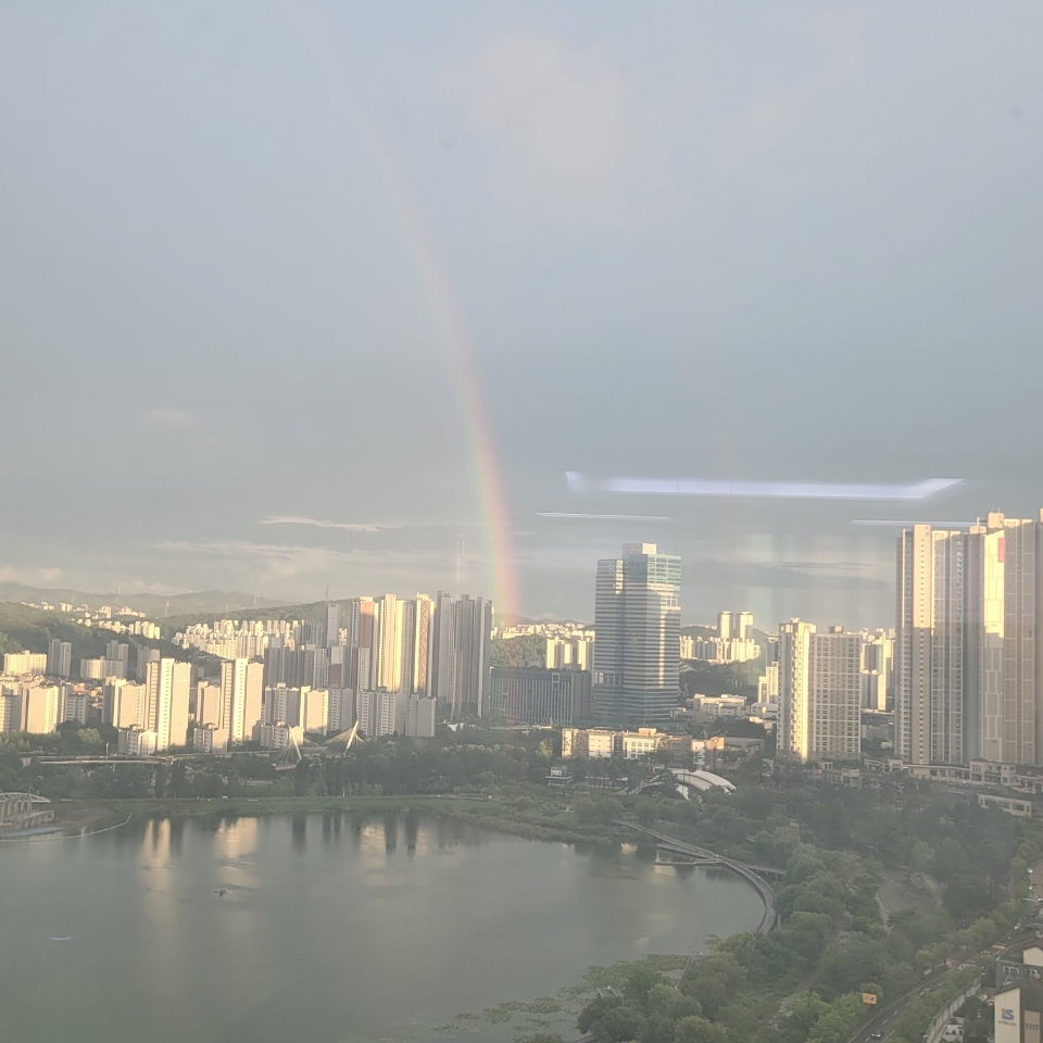 A vivid rainbow arches across the sky after a rain shower.