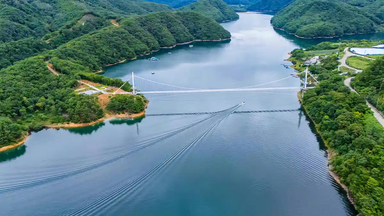 The Sangmuryong Bridge over Paro Lake in Yanggu. Yanggu, including Sangmuryong village, shouldered national defense and water supply responsibilities for 50 to 80 years, incurring an estimated 3 trillion won ($2.17 billion) in losses while receiving only about 2 billion won in infrastructure support over the same period. The isolated Seoho hamlet in Sangmuryong 2-ri finally gained road access to the town center after the bridge was built — residents had previously relied on motorboats they purchased themselves. The community, which endured decades of hardship, is now planning a Dancing Dragon festival in early October around National Foundation Day. "We will make our village beautiful and attract tourists," residents said, drawing admiration from across the country.