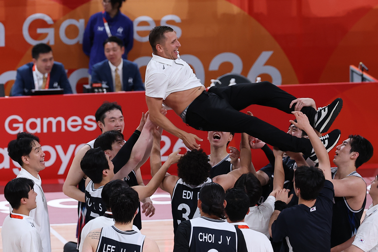 South Korean players toss their head coach Nikolajs Mazurs in the air after winning gold in men's basketball at the Asian Games at Aichi International Arena in Nagoya, Japan, on Sunday. (Yonhap)