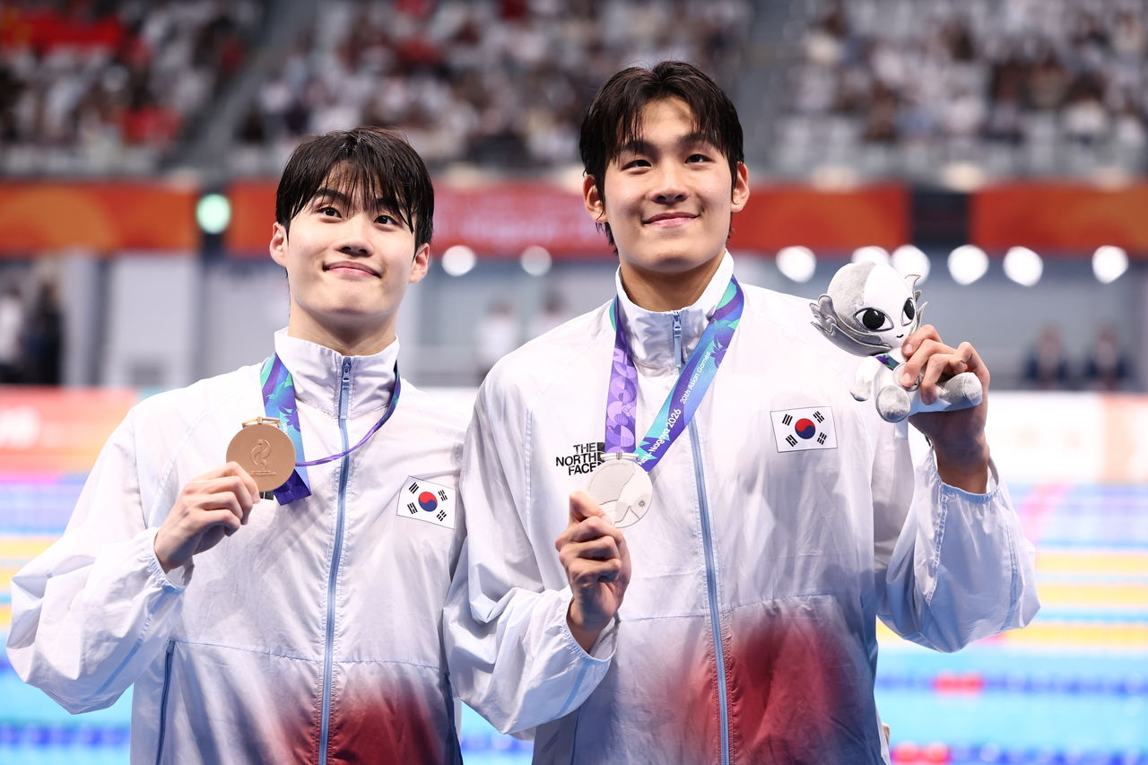 South Korean swimmers Hwang Sun-woo (left) and Kim Young-beom pose with their bronze and silver medals won in the men's 100-meter freestyle race at the Asian Games at Tokyo Aquatics Centre in Tokyo on Sunday. (Yonhap)