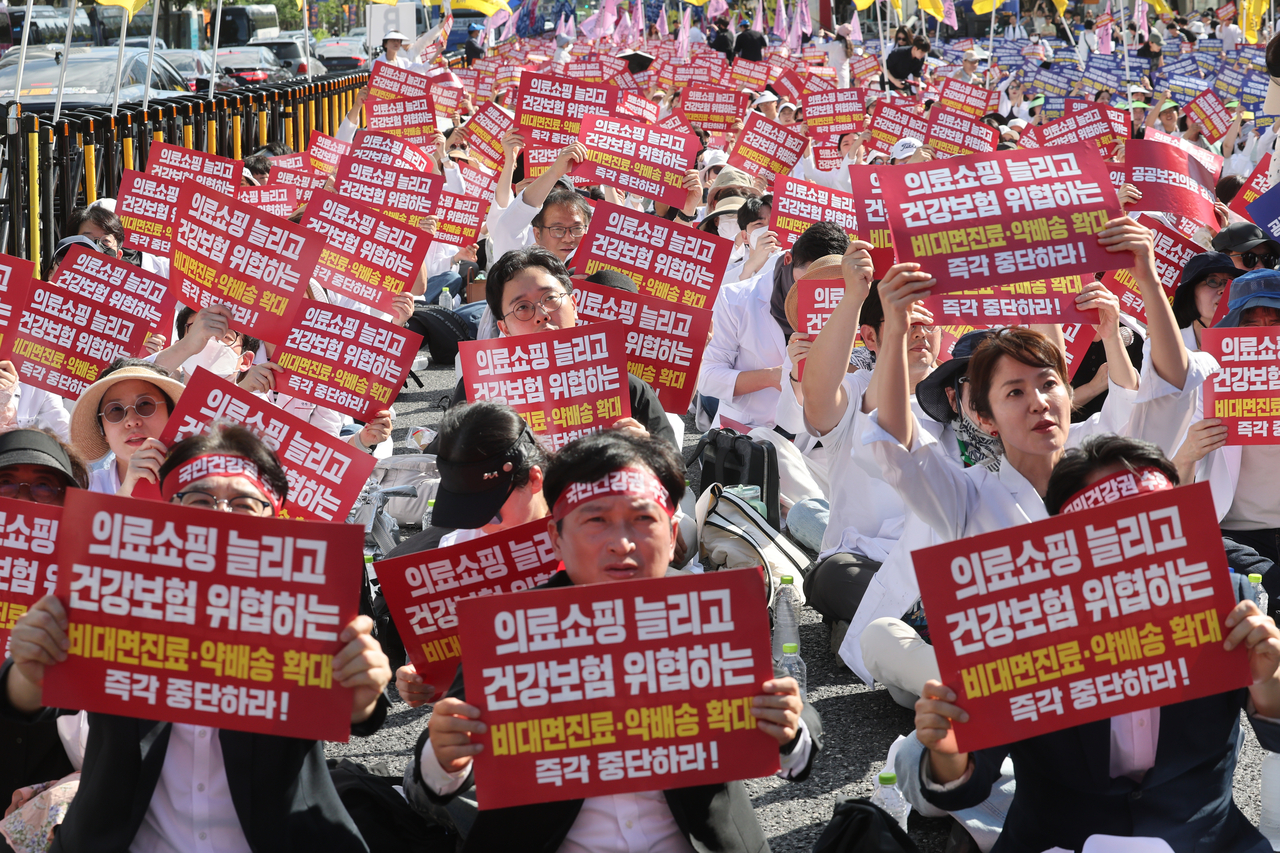 20일 서울 종로구 동화면세점 앞에서 열린 ‘전국약사 총궐기대회’에서 참가자들이 요구가 담긴 손팻말을 들고 있다. [연합]