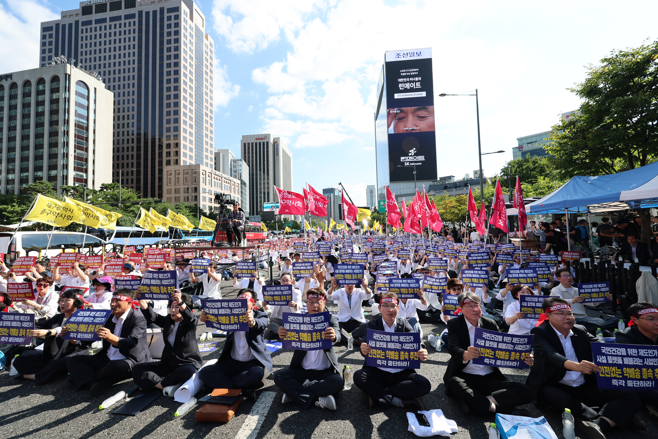 20일 서울 종로구 동화면세점 앞에서 열린 ‘전국약사 총궐기대회’에서 참가자들이 요구가 담긴 손팻말을 들고 있다. [연합]