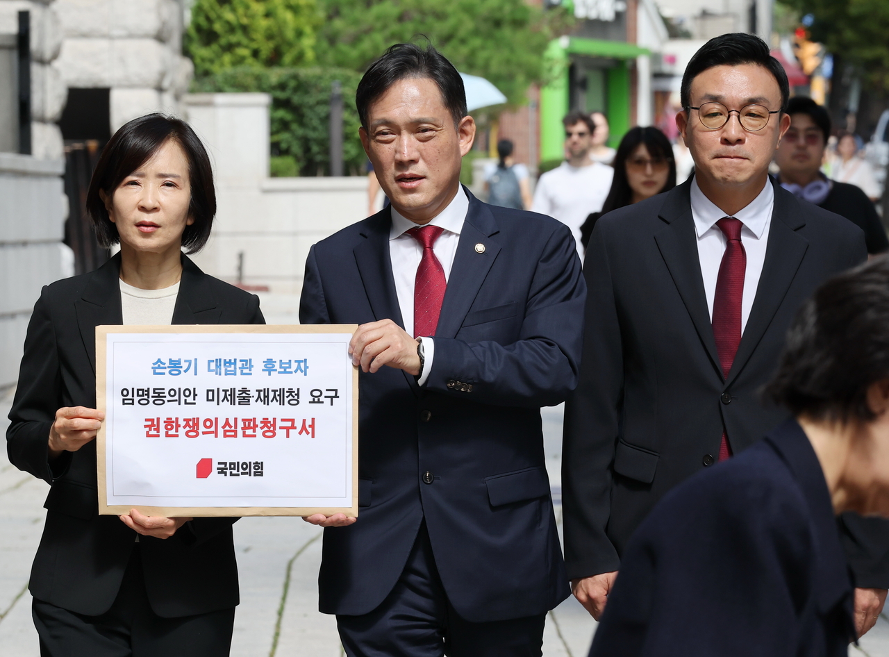 21일 최수진(왼쪽부터) 국민의힘 원내수석대변인, 김태규 법률자문위원장, 최지우 법률자문부위원장이 손봉기 대법관 후보자의 임명동의안 미제출 재제청 요구 권한쟁의심판서를 들고 서울 종로구 헌법재판소 민원실로 향하고 있다.  국민의힘은 지난 20일 청와대가 조희대 대법원장의 대법관 후보 제청을 반려하며 재제청을 요구한 것에 대해 헌법재판소에 권한쟁의심판을 청구하기로 했다. [연합]