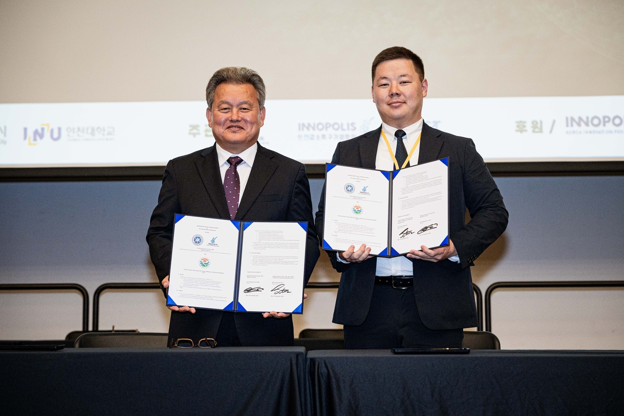 Professor Lee Hee-kwan (left) of Incheon National University and Esentur Djamalov from the Climate Finance Center in Kyrgyzstan pose for a photo after signing a memorandum of understanding. (Incheon Innovation Cluster)