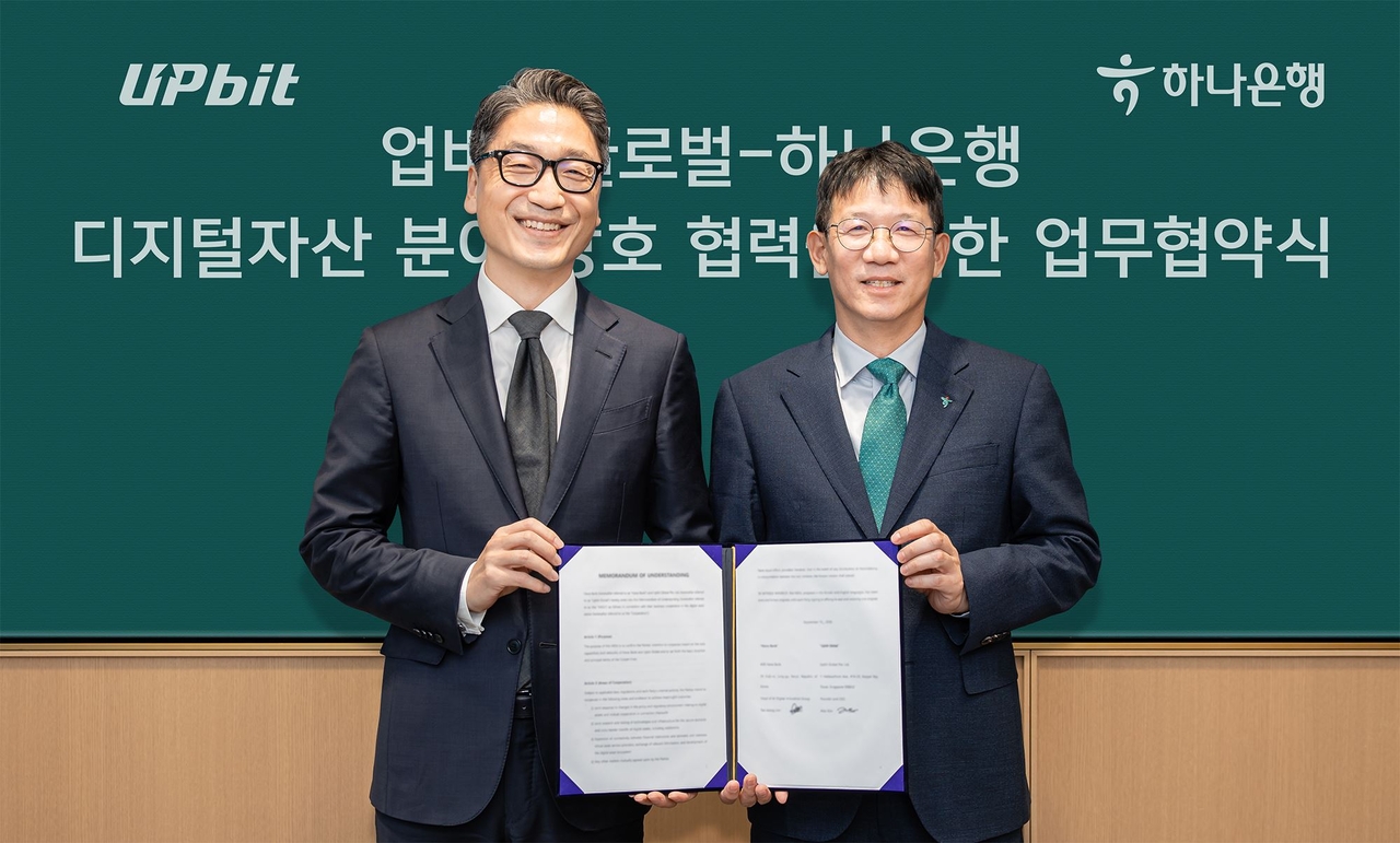 Hana Bank and Upbit Global signed an MOU at Hana Bank's headquarters in Jung-gu, Seoul, on Sept. 15 to cooperate on digital assets. Kim Guk-hyeon, chief executive of Upbit Global (left), and Eom Tae-seong, head of Hana Bank's AI Digital Innovation Group, pose for a photo after the signing ceremony. [Hana Bank]