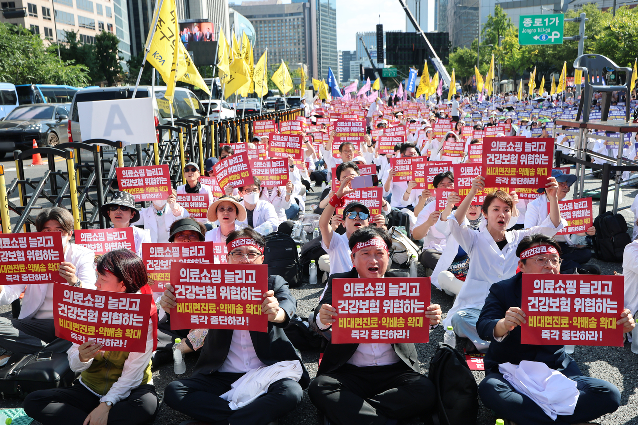 20일 서울 종로구 동화면세점 앞에서 열린 ‘전국약사 총궐기대회’에서 참가자들이 요구가 담긴 손팻말을 들고 있다. [연합]
