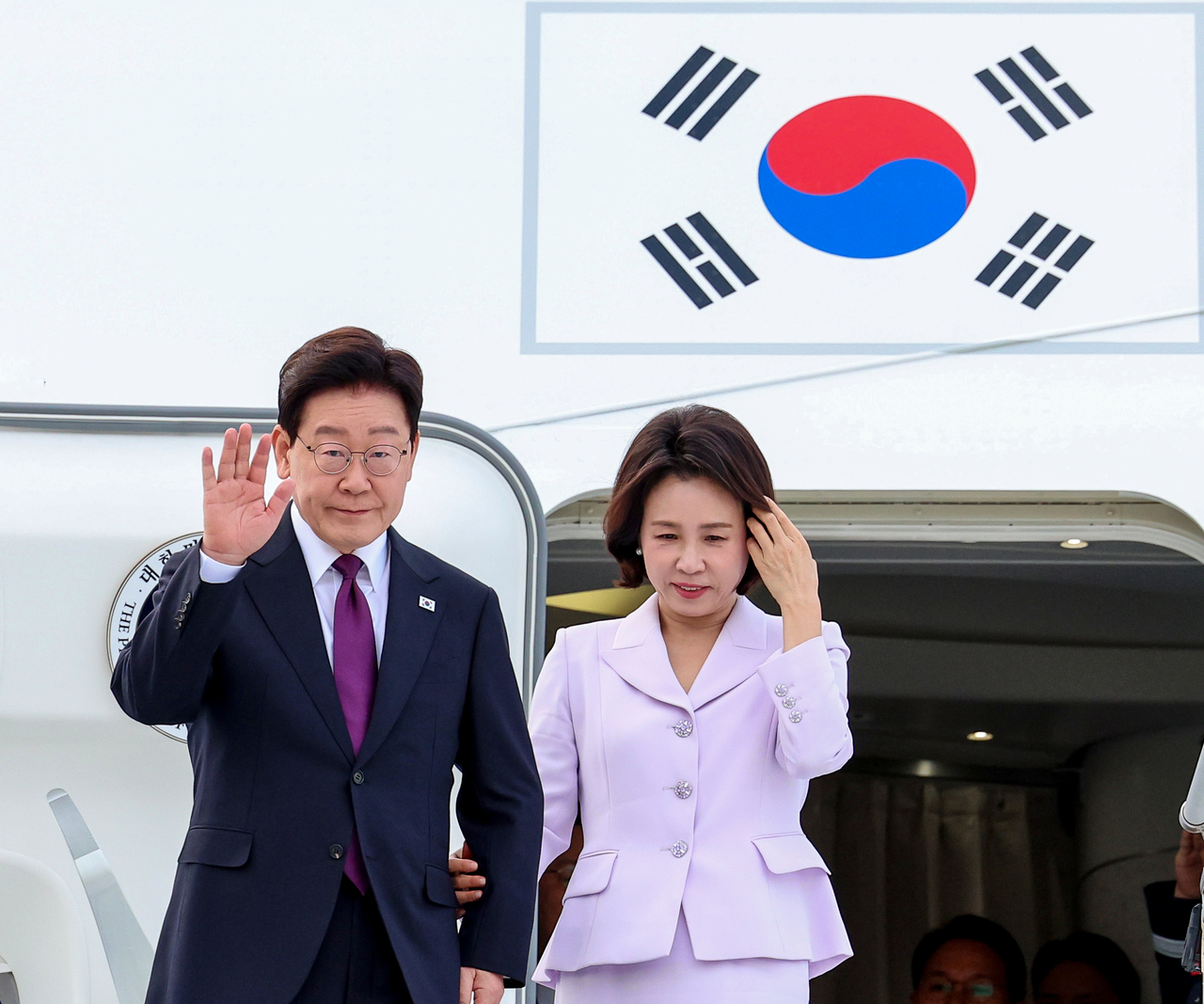 이재명 대통령과 김혜경 여사가 21일(현지시간) 미국 뉴욕 JFK 국제공항에 도착한 공군 1호기에서 환영객에게 인사하고 있다. [연합]