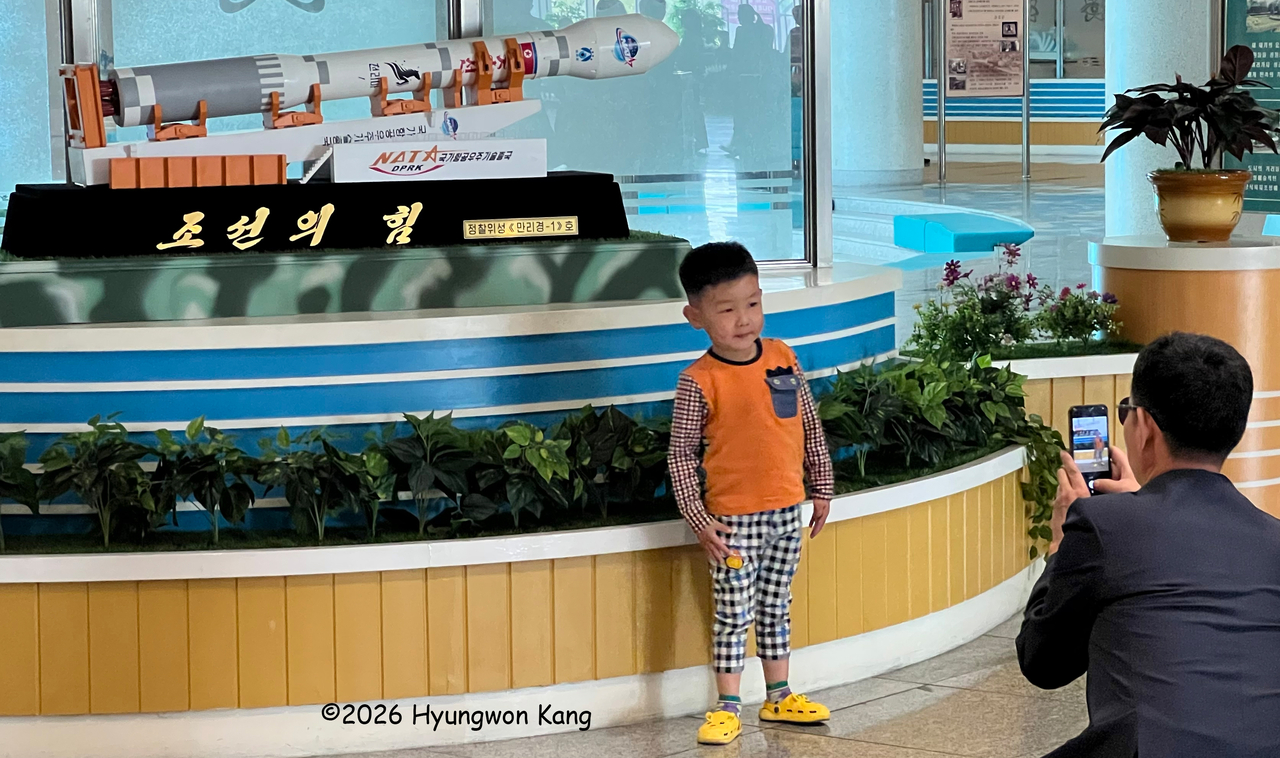 A young boy has his picture taken in front of a model of North Korea's Malligyong-1 satellite at the Sci-Tech Complex in Pyongyang on April 16. North Korea said Malligyong-1, launched on November 21, 2023, was its first military reconnaissance satellite successfully placed into orbit. (Hyungwon Kang)