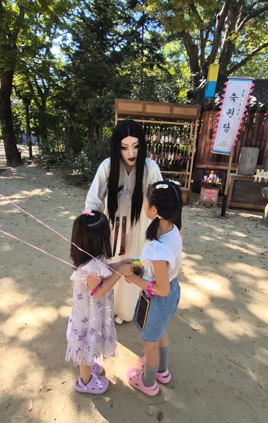 Kang Yoon-jung, dressed as a virgin ghost, talks to two sisters at the Korean Folk Village on Sept. 15. (Choi Jae-hee / The Korea Herald)