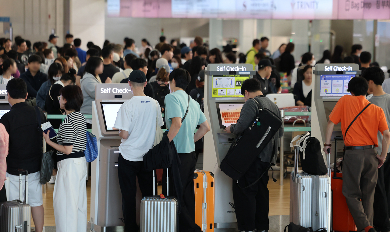Travelers use self-service check-in kiosks at Terminal 1 of Incheon Airport on Wednesday, a day before the Chuseok holiday begins. (Yonhap)