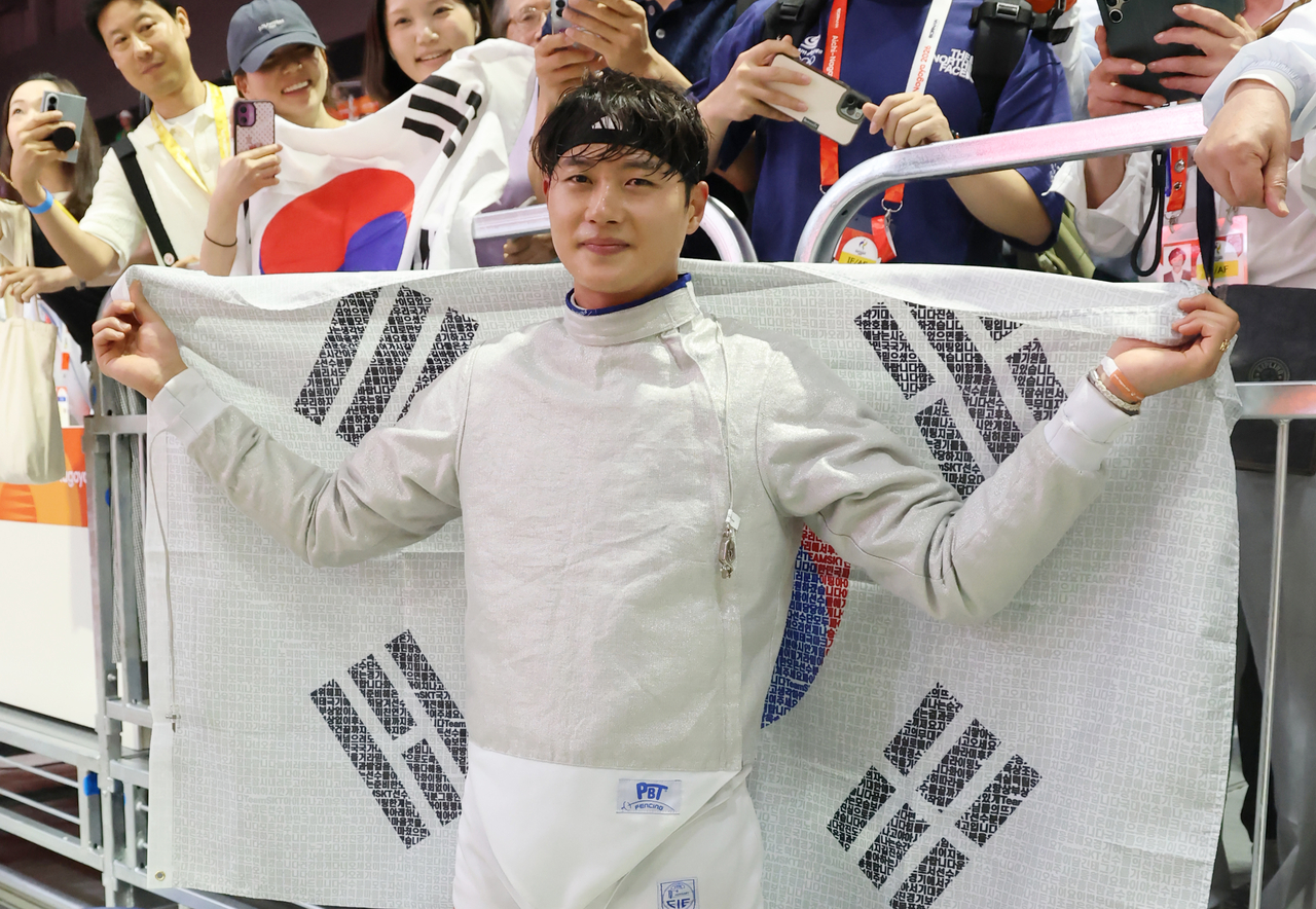 23일 일본 아이치현 도코나메 아이치 스카이 엑스포에서 열린 2026 아이치·나고야 아시안게임 남자 사브르 개인전 결승 경기에서 한국 오상욱이 중국의 선천펑을 상대로 승리하고 금메달을 차지한 뒤 태극기를 펼쳐들고 있다. [연합]