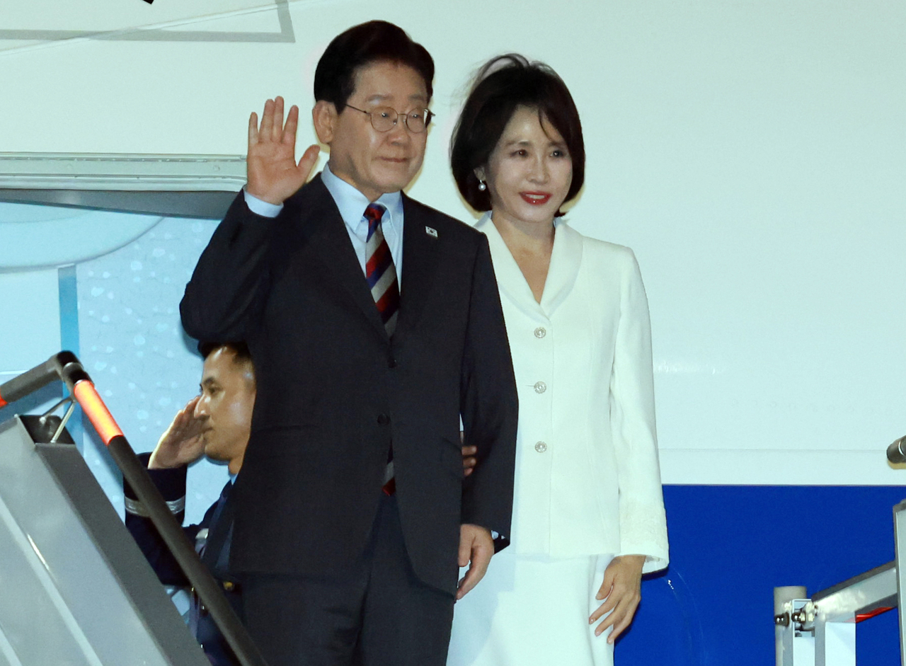 President Lee Jae Myung and first lady Kim Hea Kyung wave to a welcoming party from Air Force One after arriving at Felipe Angeles International Airport in Mexico City on Wednesday for a state visit to Mexico. (Yonhap)