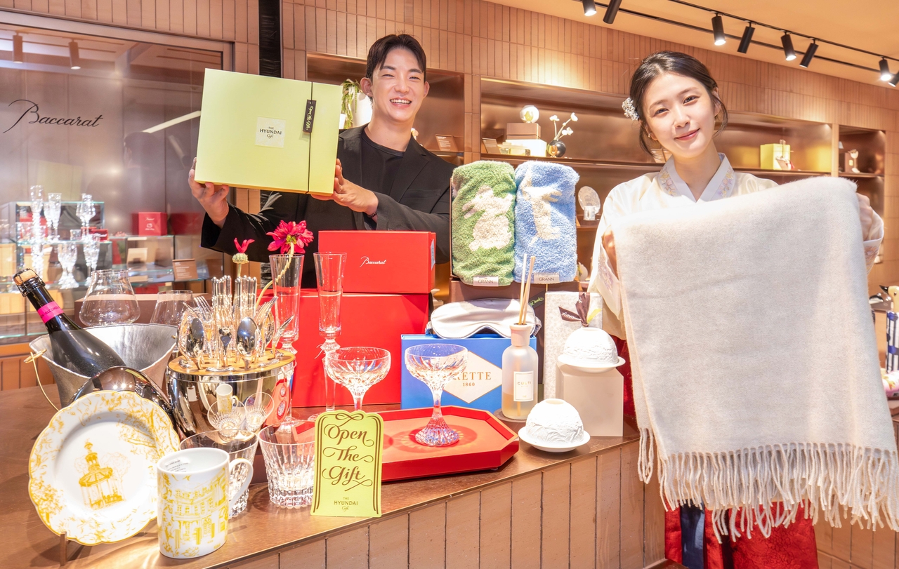 Staff members at The Hyundai Gift, a curated gift shop on the first below-ground floor of Hyundai Department Store's Trade Center branch, introduce premium living gift products for the holiday season. Featured items include a Baccarat crystal tumbler from the French luxury crystal brand, a six-piece cutlery set by Christofle, and a Bernardaud Ecume white salad plate set. [Hyundai Department Store]