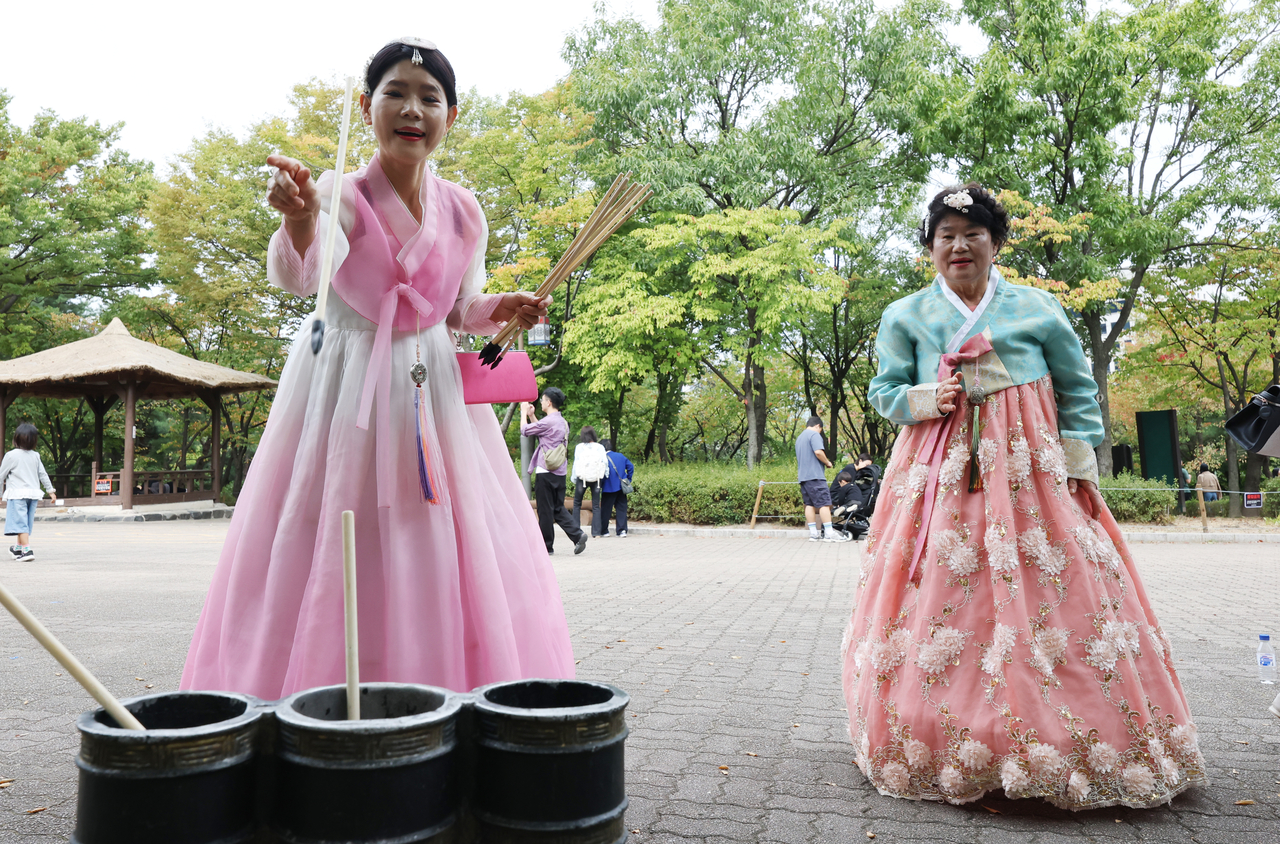 Two visitors dressed in hanbok play tuho at Namsangol Hanok Village in Seoul on Friday. (Yonhap)