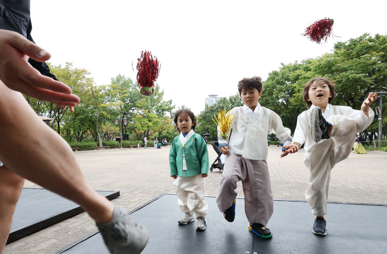 Children dressed in hanbok play jegichagi,at Namsangol Hanok Village in Seoul on Friday. (Yonhap)