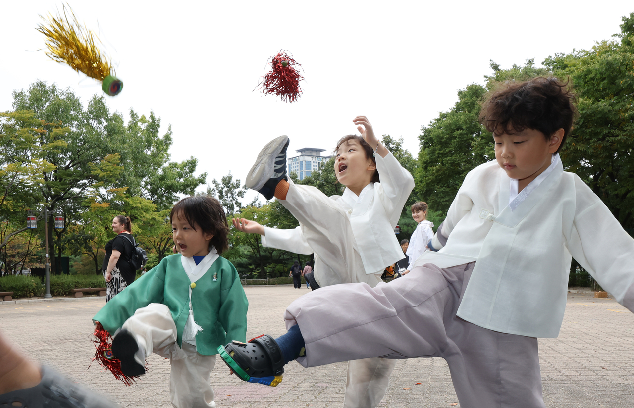 Children dressed in hanbok play jegichagi,at Namsangol Hanok Village in Seoul on Friday. (Yonhap)