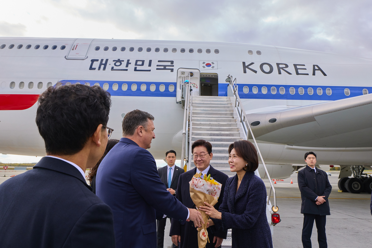 President Lee Jae Myung and first lady Kim Hea Kyung receive bouquets from greeters at Ted Stevens Anchorage International Airport in Alaska on Saturday, during a stopover on their way back to South Korea after wrapping up a trip to the United States and Mexico. (Yonhap via Pool Photo)