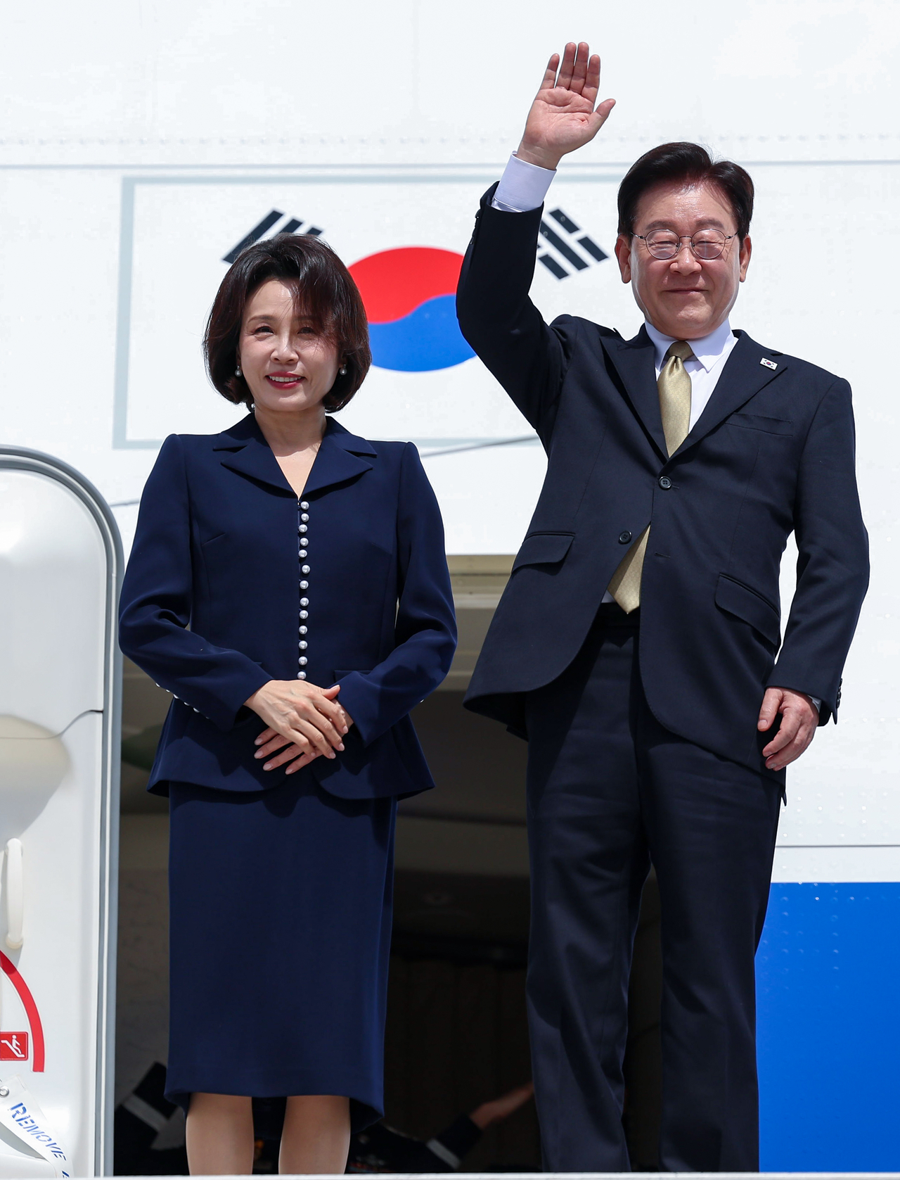 President Lee Jae Myung and first lady Kim Hye Kyung wave to well-wishers aboard the presidential aircraft at Felipe Angeles International Airport in Mexico City on Saturday, following the conclusion of their state visit to Mexico. (Yonhap)