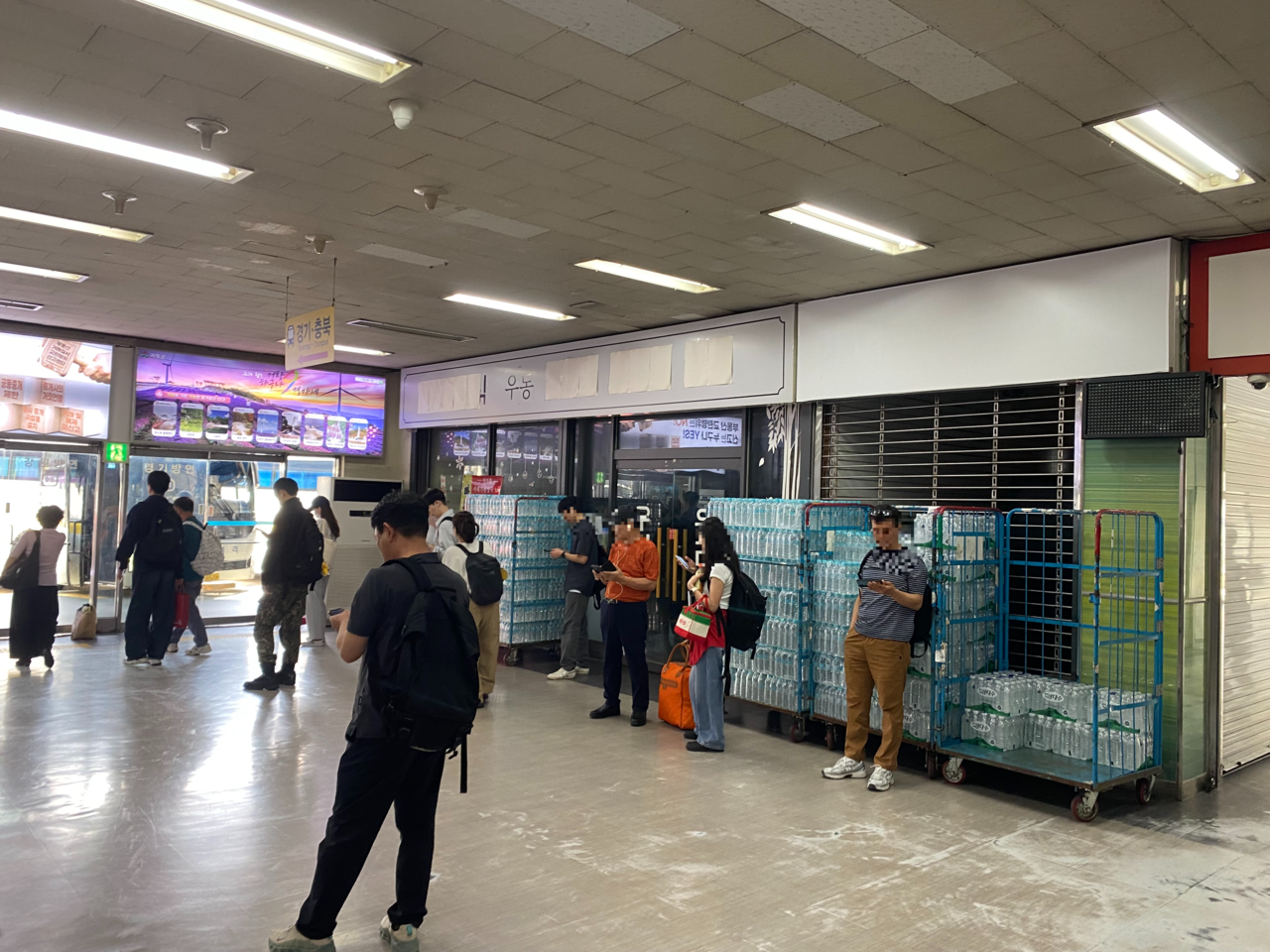 Passengers wait for their buses in front of closed shops at Nambu Terminal in southern Seoul on Wednesday. (Lim Jae-seong/The Korea Herald)