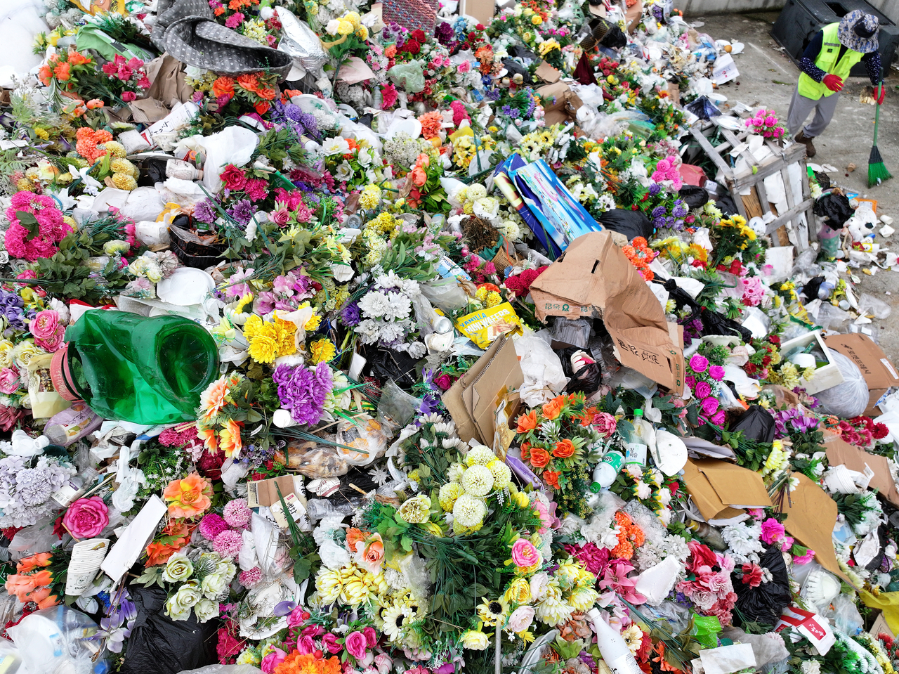 A worker sorts through discarded artificial flowers at a cemetery in Gyeongju, North Gyeongsang Province, Monday, on the first working day after the four-day Chuseok holiday.