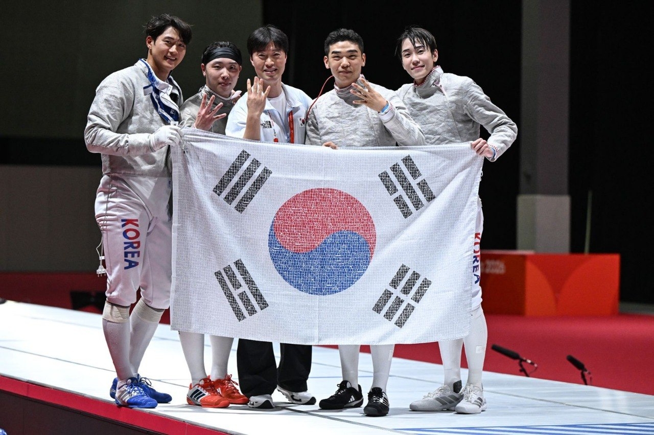 2026 아이치·나고야 아시안게임 펜싱 남자 사브르 단체전에서 4연패를 달성한 대한민국 대표팀 선수단이 국민 응원 메시지가 담긴 태극기를 들고 기념 촬영하는 모습 [SKT 제공]