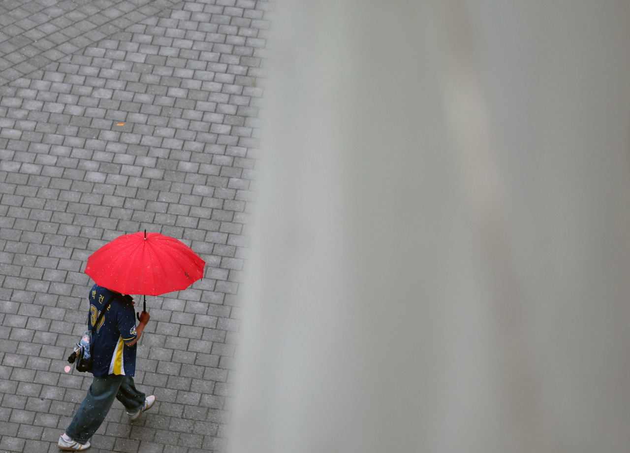 A baseball fan walks with an umbrella at Changwon NC Park in Masan Hoewon-gu, Changwon, South Gyeongsang Province. [Yonhap]
