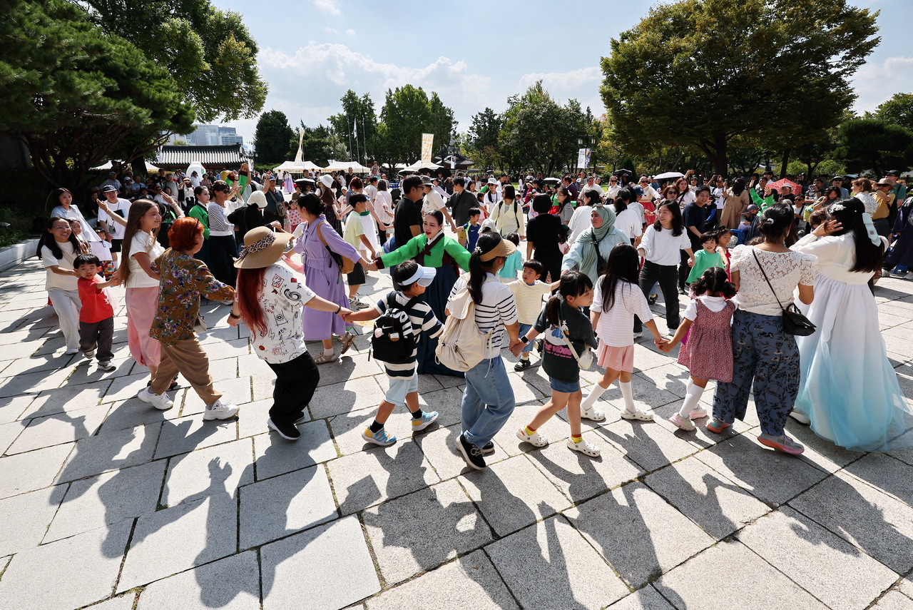 Dancers, local residents and foreign tourists take part in a traditional circle dance known as Ganggangsullae during the “Chuseok Together” event at the National Folk Museum of Korea in Jongno-gu, Seoul, Sunday, on the final day of the Chuseok holiday. (Yonhap)