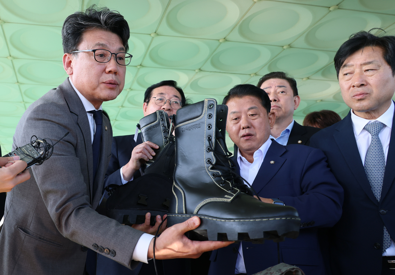 South Korean lawmakers who are members of the National Defense Committee at the National Assembly, including committee chair Rep. Jin Sung-joon (left), look at a protective gear for soldiers in duty at a military post in Yeoncheon-gun, Gyeonggi Province, as they were briefed on Monday about the recent blast in the Demilitarized Zone. (Pool photo via Yonhap)