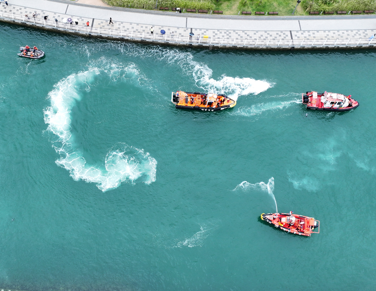 Coast Guard vessels spray water from water cannons in a bid to steer a shark toward the open sea on Tuesday at a waterfront park near North Port in Busan. (Yonhap)