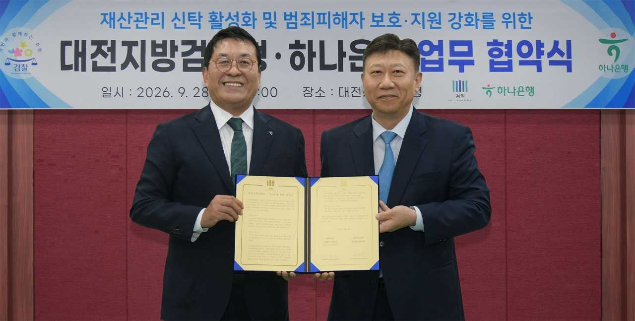 Kim Jin-woo (left), head of Hana Bank's asset management group, poses with Kim Do-wan (right), chief prosecutor of the Daejeon District Prosecutors Office, at a signing ceremony held Monday. [Hana Bank]