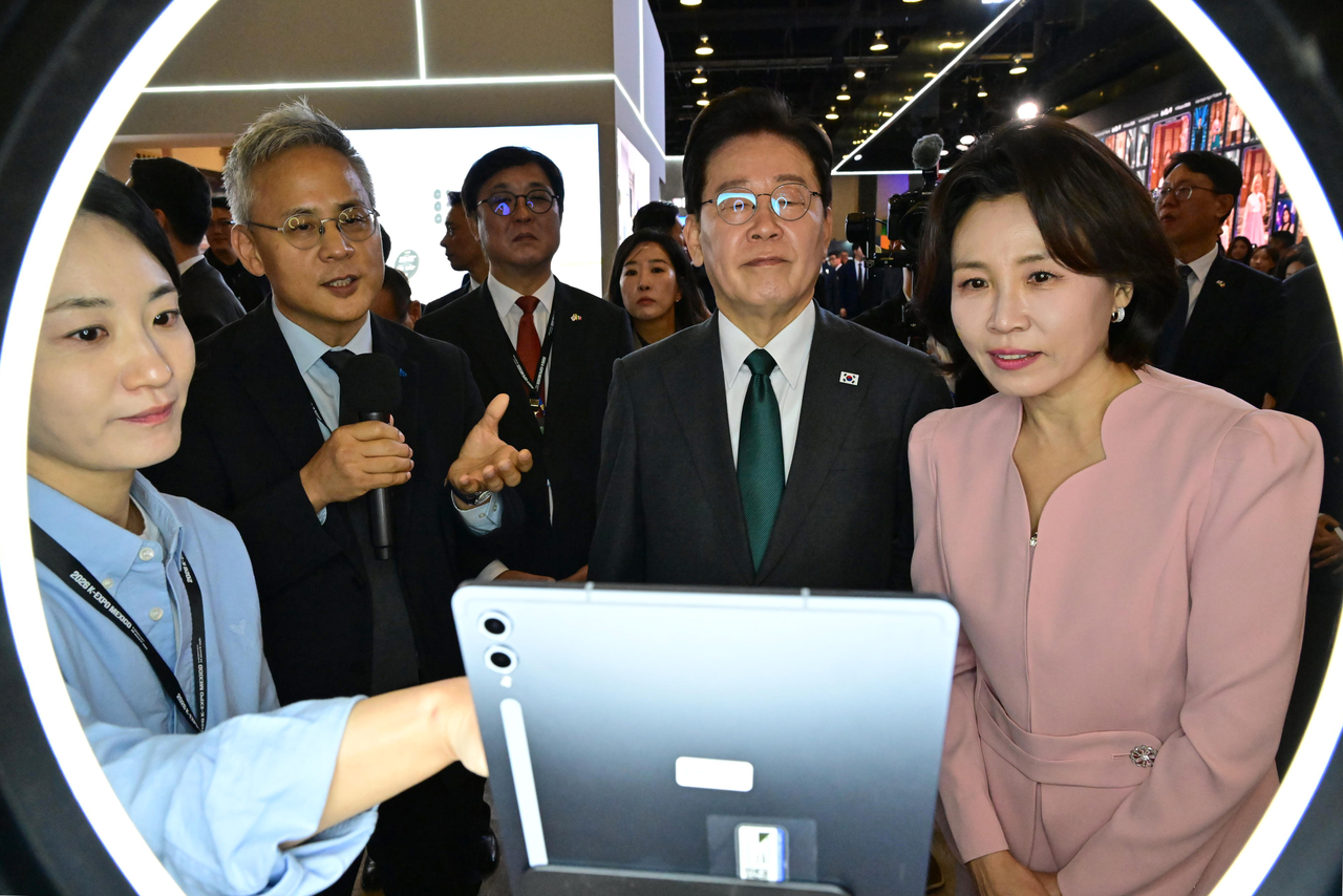Amorepacific CEO Kim Seung-hwan (second from left) explains the company's skin diagnostic device to President Lee Jae Myung (second from right) and first lady Kim Hea Kyung (right) at the Amorepacific booth at the 2026 K-Expo Mexico on Saturday. (Yonhap)