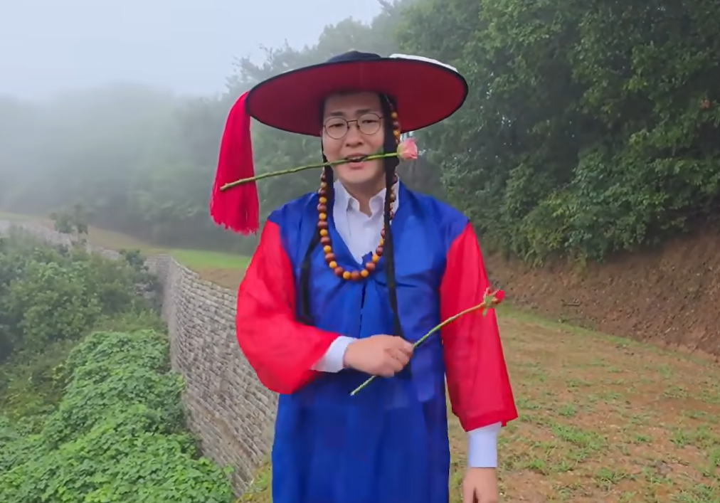 Chungju Mayor Lee Dong-seok, dressed as a traditional local magistrate, holds a rose between his teeth at Jangmi Fortress in Chungju. (Screenshot from Lee Dong-seok TV)
