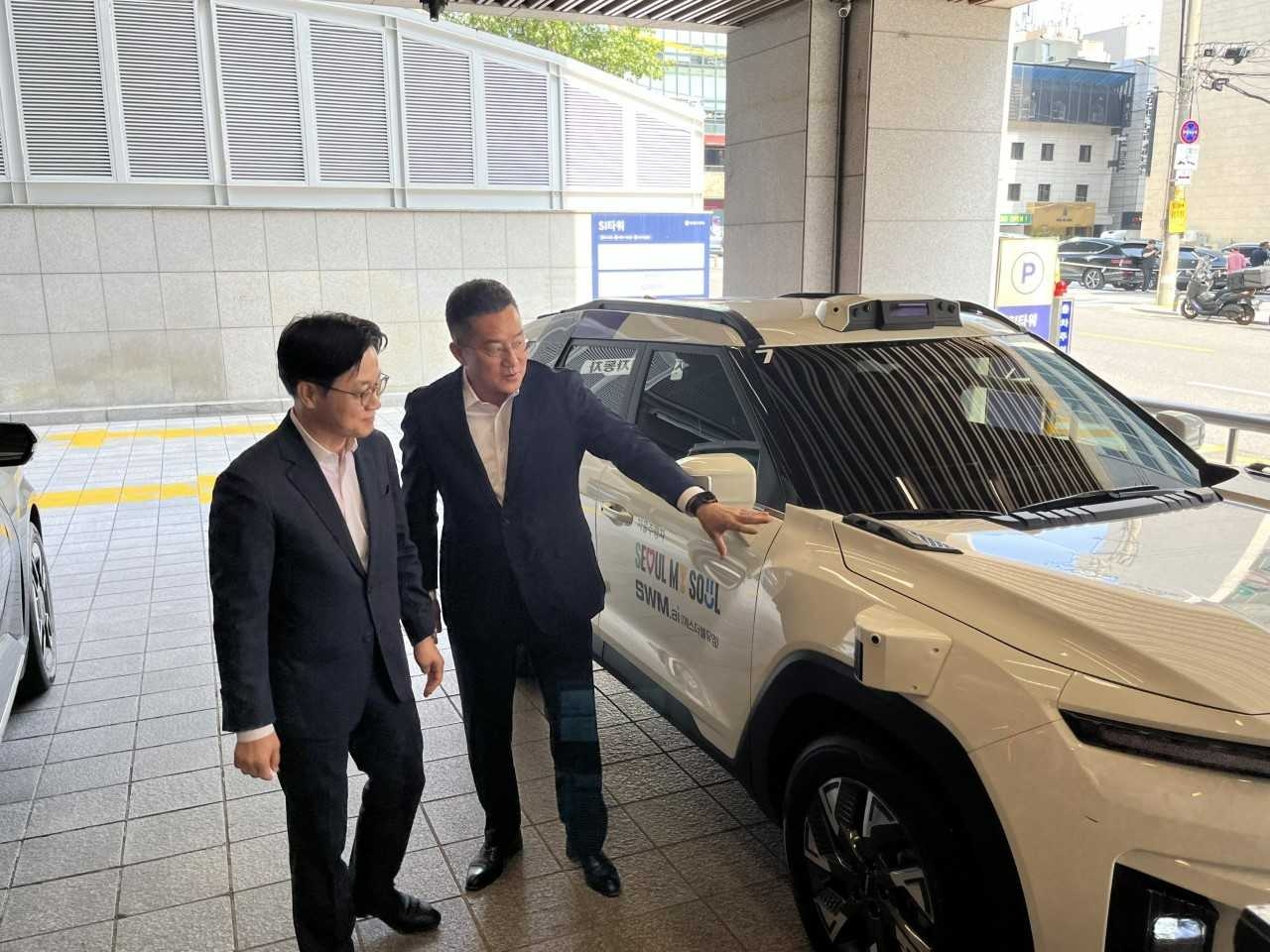 [사진] 김기혁 SWM.ai 대표가 강남 도심 로보택시 시승을 앞두고 김정관 산업통상부 장관에게 관련 기술을 설명하고 있다. [사진=SWM.ai 제공]