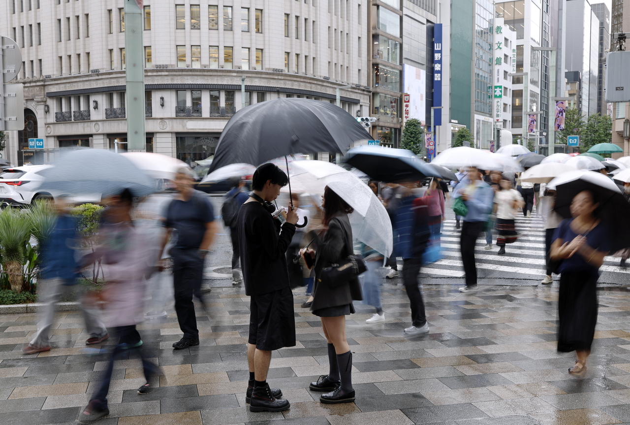 People walk with umbrellas in the rain along the Ginza shopping district in Tokyo on Sept. 29, 2026. [EPA]