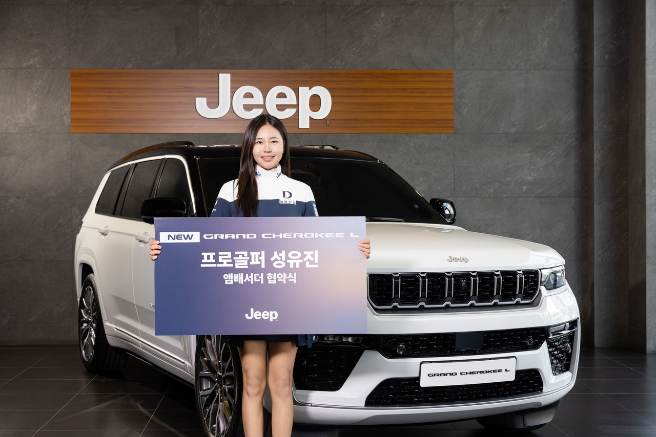 Seong Yu-jin poses in front of a Jeep Grand Cherokee L at an ambassador signing ceremony.