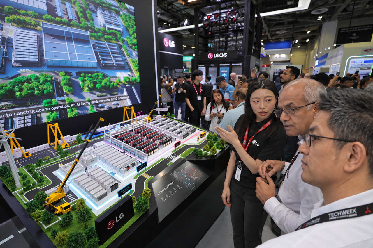 Visitors examine a modular AI factory exhibition model at the LG booth during Data Centre World Asia 2026 in Singapore. [LG CNS]