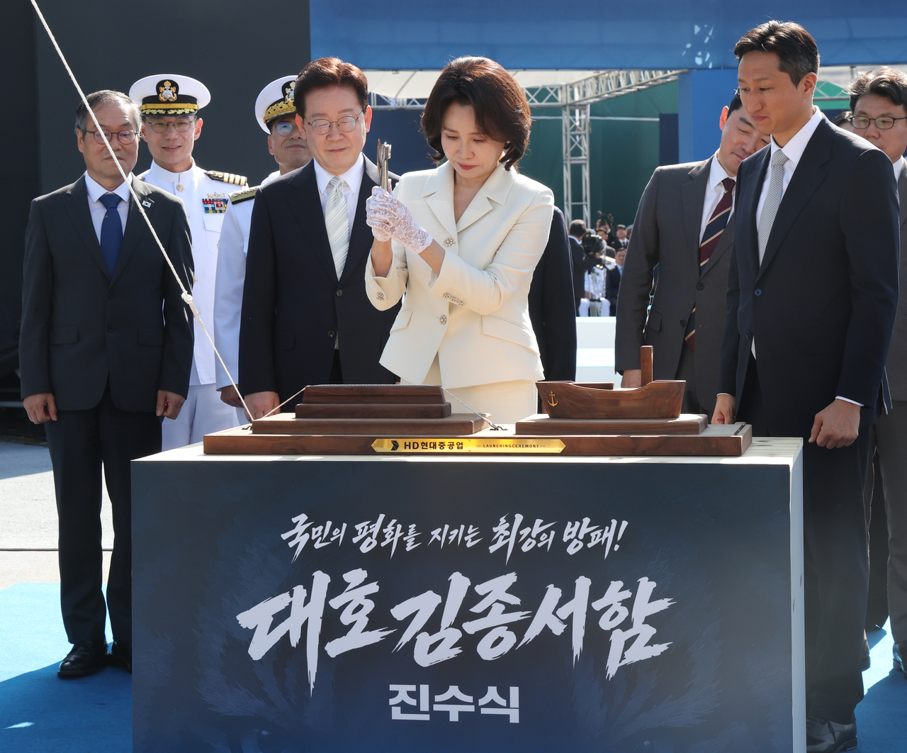 First lady Kim Hea Kyung (front) cuts the ceremonial rope for the launch of the ROKS Daeho Kim Jong Seo Aegis destroyer, as President Lee Jae Myung and HD Hyundai Chair Chung Ki-sun (right) look on in Ulsan on Wednesday. (Yonhap via pool photo)