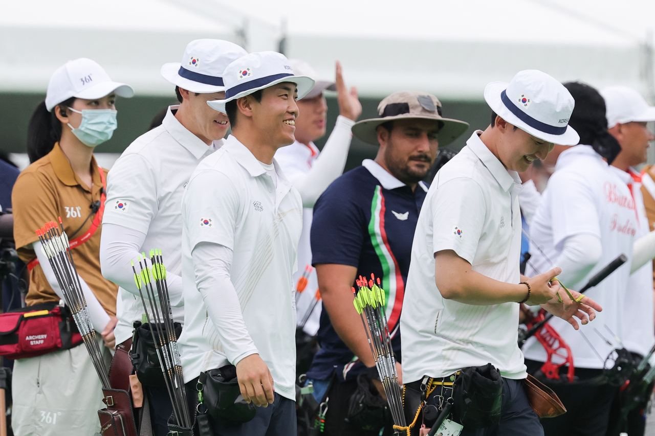 Choi Yong-hee (from left), Choi Eun-gyu and Kim Jong-ho of South Korea walk toward the target to check their arrows after defeating Iran in the men's EMC team quarterfinals at the 2026 Aichi-Nagoya Asian Games at the Okazaki Central General Park multipurpose plaza in Aichi Prefecture, Japan, on Sunday. [Yonhap]